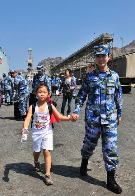 2015年3月，也门，海军女战士牵着一名小女孩的手准备登上军舰。